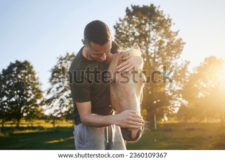 Man is embracing of therapy horse on meadow at sunset. Themes hippo therapy, care and friendship between people and animals.
 Royalty-Free Stock Photo #2360109367