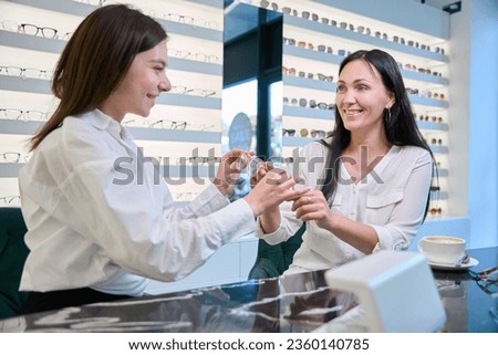 Friendly optician demonstrating new prescription glasses to customer Royalty-Free Stock Photo #2360140785