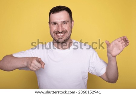 Portrait of excited young man holding something invisible in hand. Positive male showing empty mockup place for ad, banner. 
