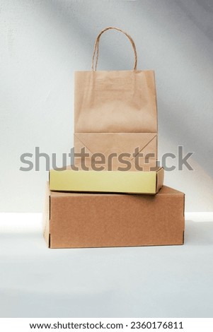 Packaging of eco-materials. Cardboard boxes and paper bag on a light background. Concept saving the planet from undetectable debris. Front view