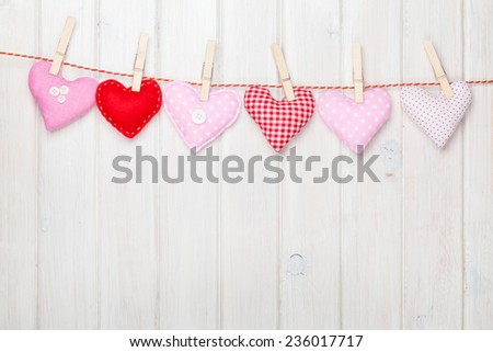 Valentines day toy hearts hanging on rope over white wooden background with copy space