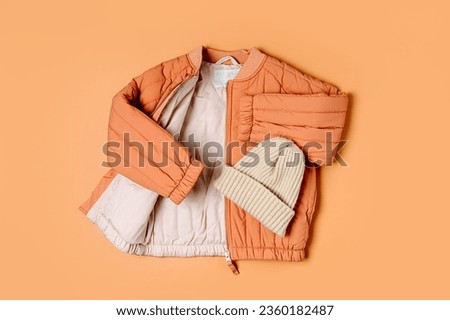 Stylish terracotta children's autumn jacket and knitted hat. Fashion kids outfit for for spring, autumn or winter. Flat lay, top view Royalty-Free Stock Photo #2360182487