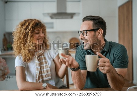 Young couple caucasian man and woman husband and wife enjoy cup of tea or coffee in the morning at home happy smile daily morning routine real people Royalty-Free Stock Photo #2360196739