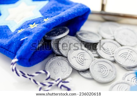 Blue dreidel with silver tokens on a white background