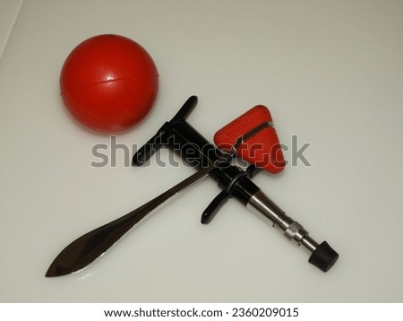Chiropractic adjustment tool with a red reflex hammer and a red stress ball Royalty-Free Stock Photo #2360209015