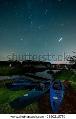 Kayaking marina at night, destroyed metal pedestrian and road bridge, star trails in the sky