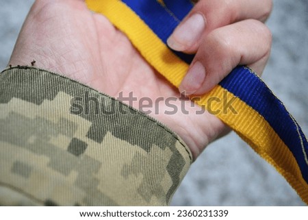 a military woman clutched a blue and yellow ribbon in her hands