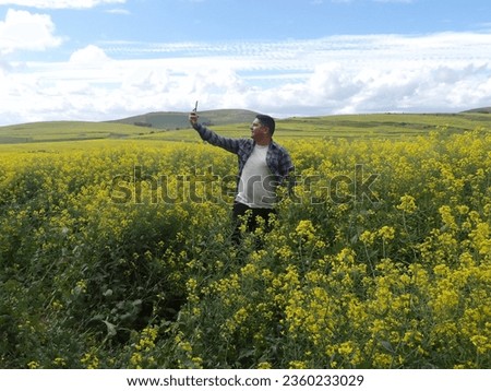 Man taking a picture in a field of Canola