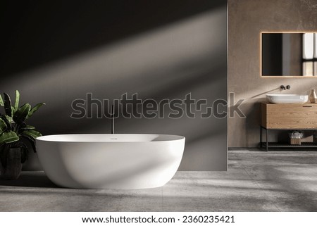 minimalist bathroom interior, concrete floor and gray and beige walls, bathroom cabinet, bathtub. Royalty-Free Stock Photo #2360235421