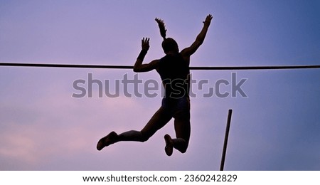 A female pole vaulter (body silhouette) jumping with a beautiful sky in the background. Track and field athlete. Woman pole-vaulting. Pole vault competition Royalty-Free Stock Photo #2360242829
