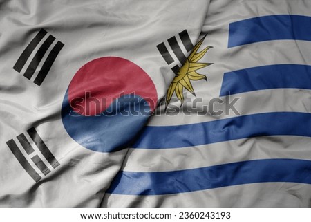 big waving national colorful flag of south korea and national flag of uruguay . macro