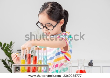 little girl Wear a brightly colored shirt working with test tube science experiment in white room