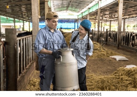 Young cowman and cowgirl holding aluminium milk container working in dairy farming