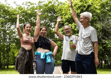 Group of sportmen and women rasing hands feeling happy after doing exercise in green park Royalty-Free Stock Photo #2360291861