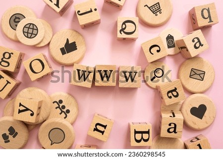 Wooden toy screened with "WWW" letters and icons on a pink background.