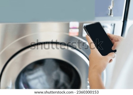 Isolated mockup black screen with clipping path. Asian man using self-service - automatic washing machine, Asian man using application on smartphone to access self service KIOS laundry machine.