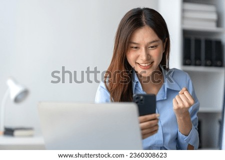 Asian businesswoman raising her hand with a happy expression and looking at her phone The businesswoman was delighted to receive an email informing her of her annual bonus. concept of success Royalty-Free Stock Photo #2360308623