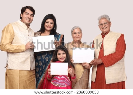 Indian happy family holding white frame shaped carboard. isolated in white background. wearing traditional dresses and looking in front of the camera. festive creative concept theme.