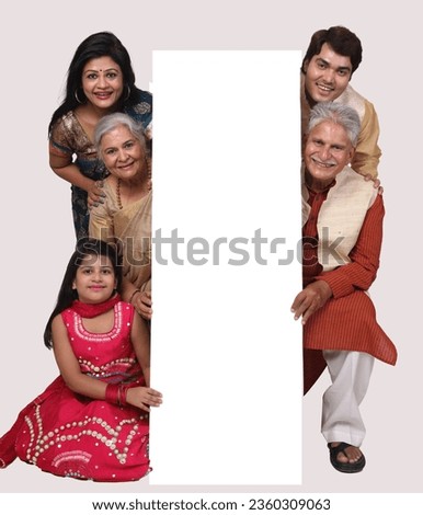 Indian happy family holding white frame shaped carboard. isolated in white background. wearing traditional dresses and looking in front of the camera. festive creative concept theme.