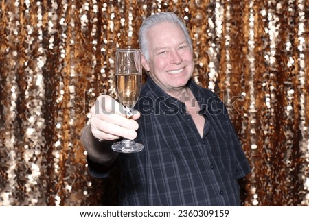 Photo Booth. Champagne. A man smiles and Toast to friends and family with a glass of Champagne while having his pictures taken in a Photo Booth. Champagne is Perfect for all Photo Booths. Cheers. 
