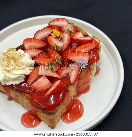Strawberry french toast with whip cream, mint, and yellow flower on a white dishes . top view, Healthy sweets, Black background, Healthy breakfast concept. Bakery picture free space for text. 