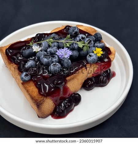 Blueberry french toast with whip cream, mint, and yellow flower on a white dishes . top view, Healthy sweets, Black background, Healthy breakfast concept. Bakery picture free space for text. 