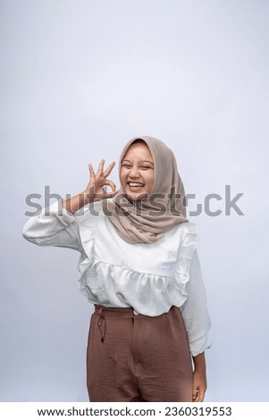 Beautiful young indonesia muslim girl says good job or well done, makes okay gesture, demonstrates symbol of approval and like. Successful expression isolated on white background.