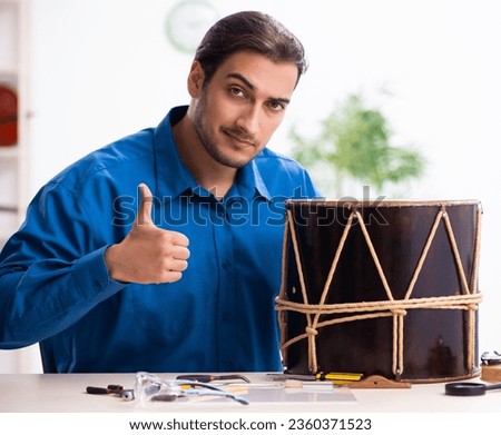 Young male repairman repairing drum