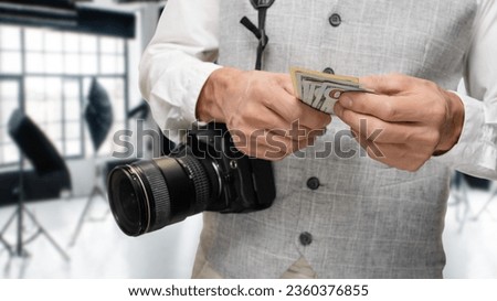 Professional male photographer holding and counting money for his work, photo conveys a sense of professionalism, dedication, and financial success in the field of photography.