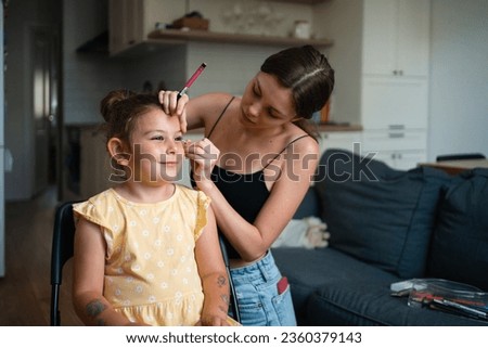 Close-up of makeup artist doing kids makeup with pink eyeliner. Small girl party or birthday day preparation. . High quality photo