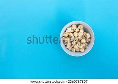 Popcorn in bowl isolated on blue background, after some edits.
