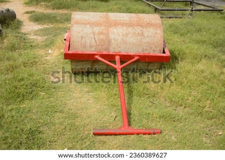 Soil roller laying of the field. Old rusty metal lawn roller on cricket field. Cricket Pitch Roller, Type of 
 Equipment's Ground Maintenance Equipment machine on grass and sports ground. 