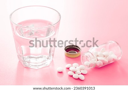 Pills and water on a pink background.