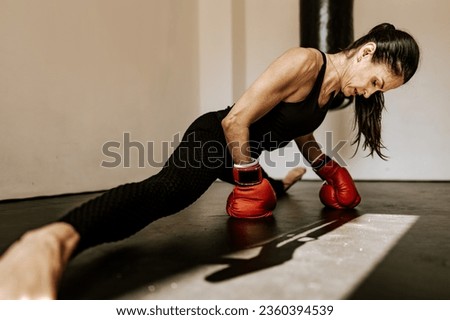 Fit woman in sportswear and red boxing gloves in a gym Royalty-Free Stock Photo #2360394539