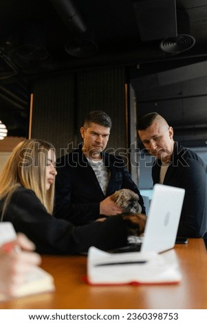 Businesswoman presents project details to colleagues using modern laptop. Fluffy Shih Tzu adds homely touch to work environment Royalty-Free Stock Photo #2360398753