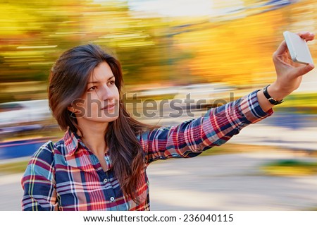 young beautiful woman taking selfie outdoor on the carousel