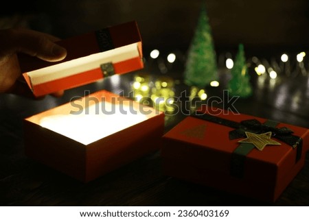 Gift boxes with a large red bow  against a background bokeh of twinkling party lights. Luxury New Year gift. Christmas gift. Christmas background with gift box. Christmastime celebration