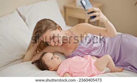 Mother and daughter lying on bed make selfie by smartphone kissing at bedroom