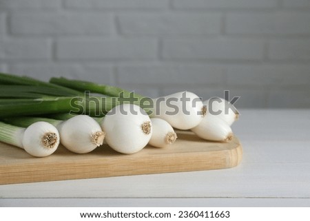 Fresh green spring onions on white wooden table, closeup. Space for text