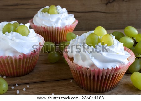 sweet cupcakes with cream and grapes