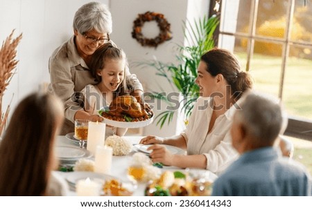 Thanksgiving Day, Autumn feast. Happy family sitting at the table and celebrating holiday. Grandparents, mother and children. Traditional dinner. Royalty-Free Stock Photo #2360414343