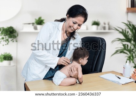 Young indian female doctor holding stethoscope and listening to baby heartbeat. Regular examining to pediatrician at clinic or hospital. Healthcare and medical concept. Royalty-Free Stock Photo #2360436337