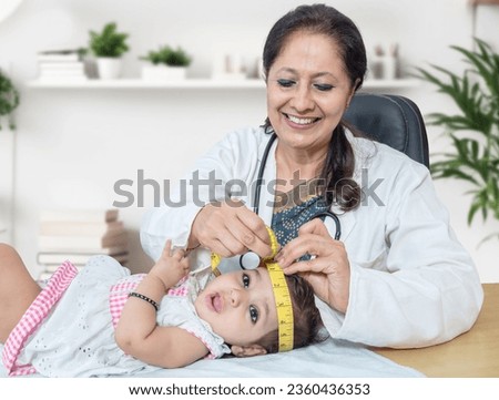 Smiling female pediatrician examines 6 months baby girl and measures the growth. Doctor using measurement tape to check baby head size. Newborn routine checkup. Royalty-Free Stock Photo #2360436353