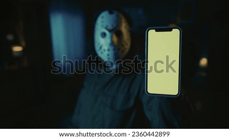 Closeup shot of horror maniac holding a smartphone, looking at the camera. Advertising area, workspace mockup.