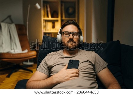 Front view of a Caucasian man with closed eyes listening music using headphones. Royalty-Free Stock Photo #2360444653