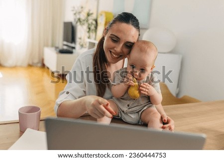 Mother is showing a video on computer to her baby.