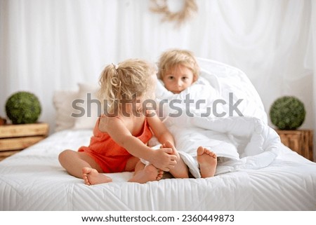 Happy positive children, tickling on the feet, having fun together, boy and girl at home having wonderful day of joy together