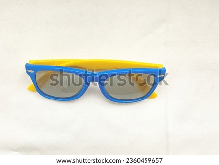 Kids Sun Glasses with blue frame and yellow shaft on white texture background with shadow