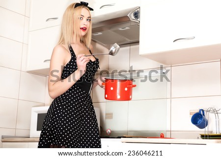 Beautiful young housewife in the kitchen. A girl holding a pot. 