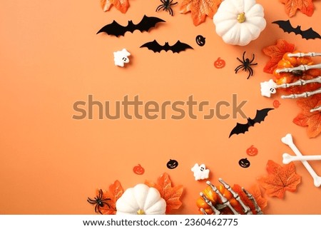Halloween flat lay composition with pumpkins, bats, spider maple leaves on pastel orange background. Flat lay, top view, copy space.